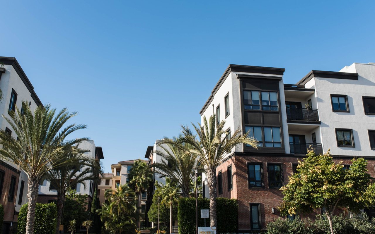 A row of apartment buildings with palm trees in front of them