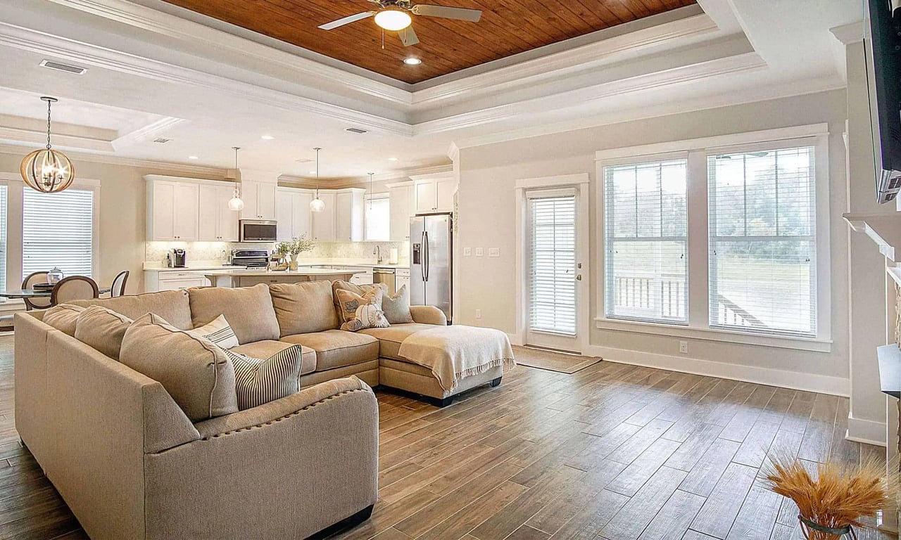 A cozy living room with wooden floors and a ceiling with wooden beams. The room is furnished with comfortable sofas and a coffee table, creating a warm and inviting atmosphere.