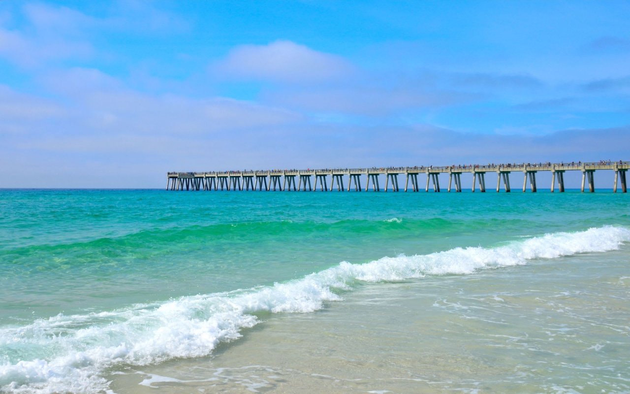 A long wooden pier that extends out into a calm ocean.