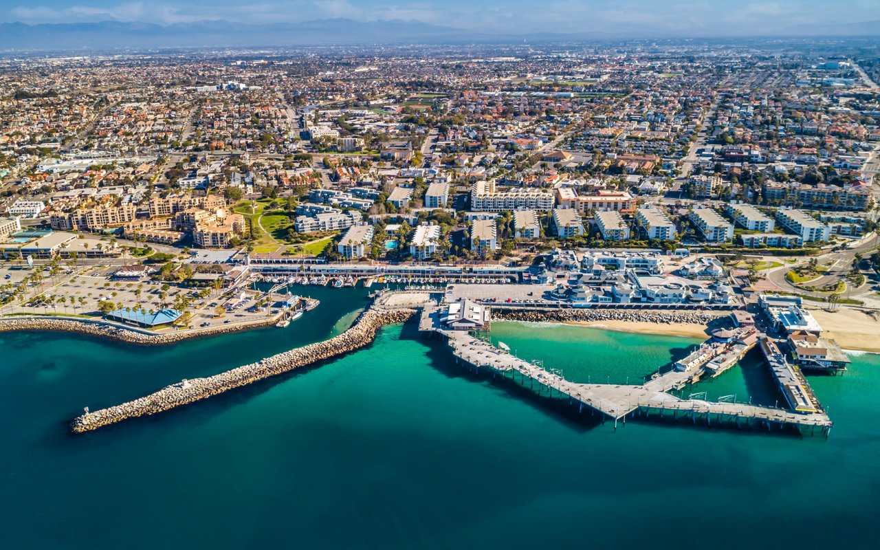 Aerial view of a coastal city with a pier, marina, and beach.