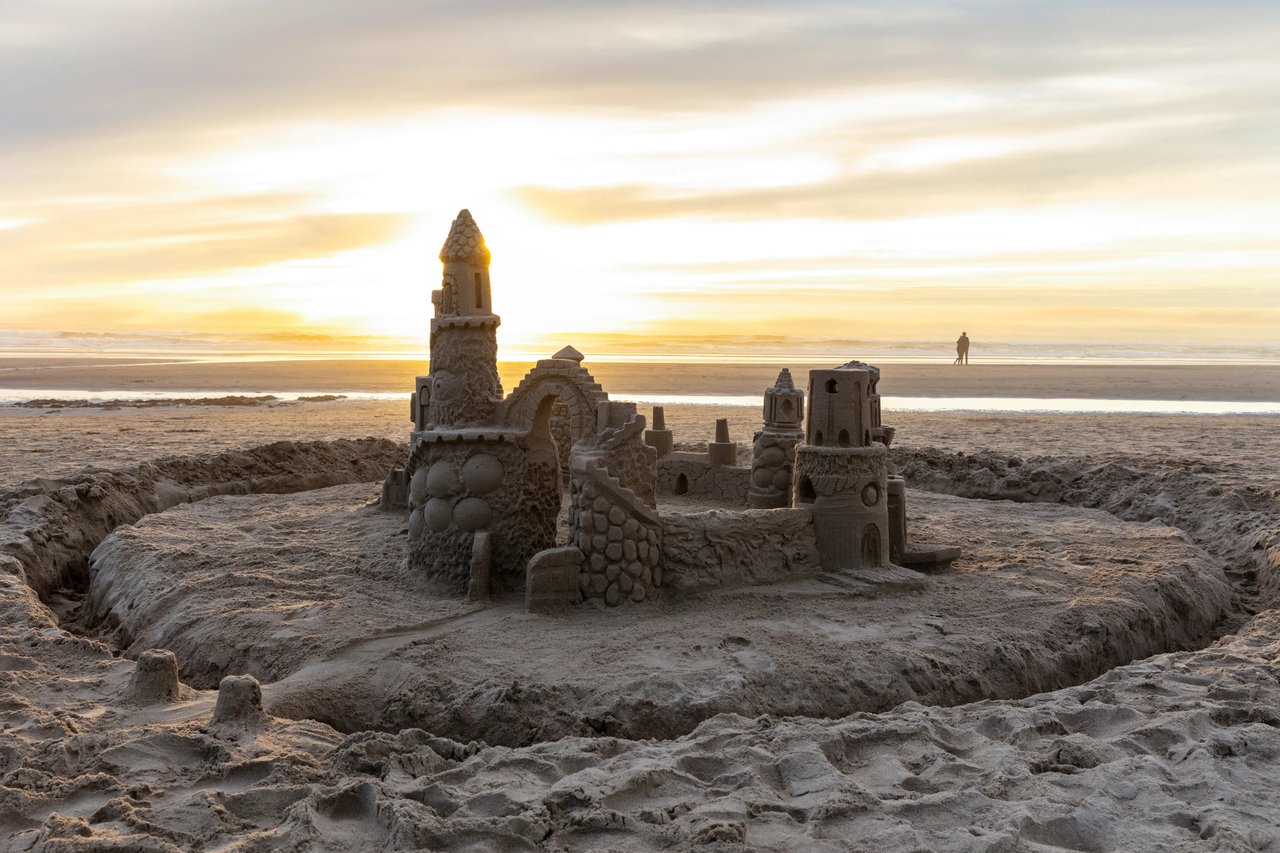 Sand castle in with sunset on the spire and a couple hugging by the ocean