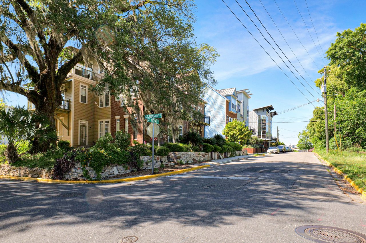 A street view in the All Saints community, showcasing residential buildings and a well-maintained road with greenery.