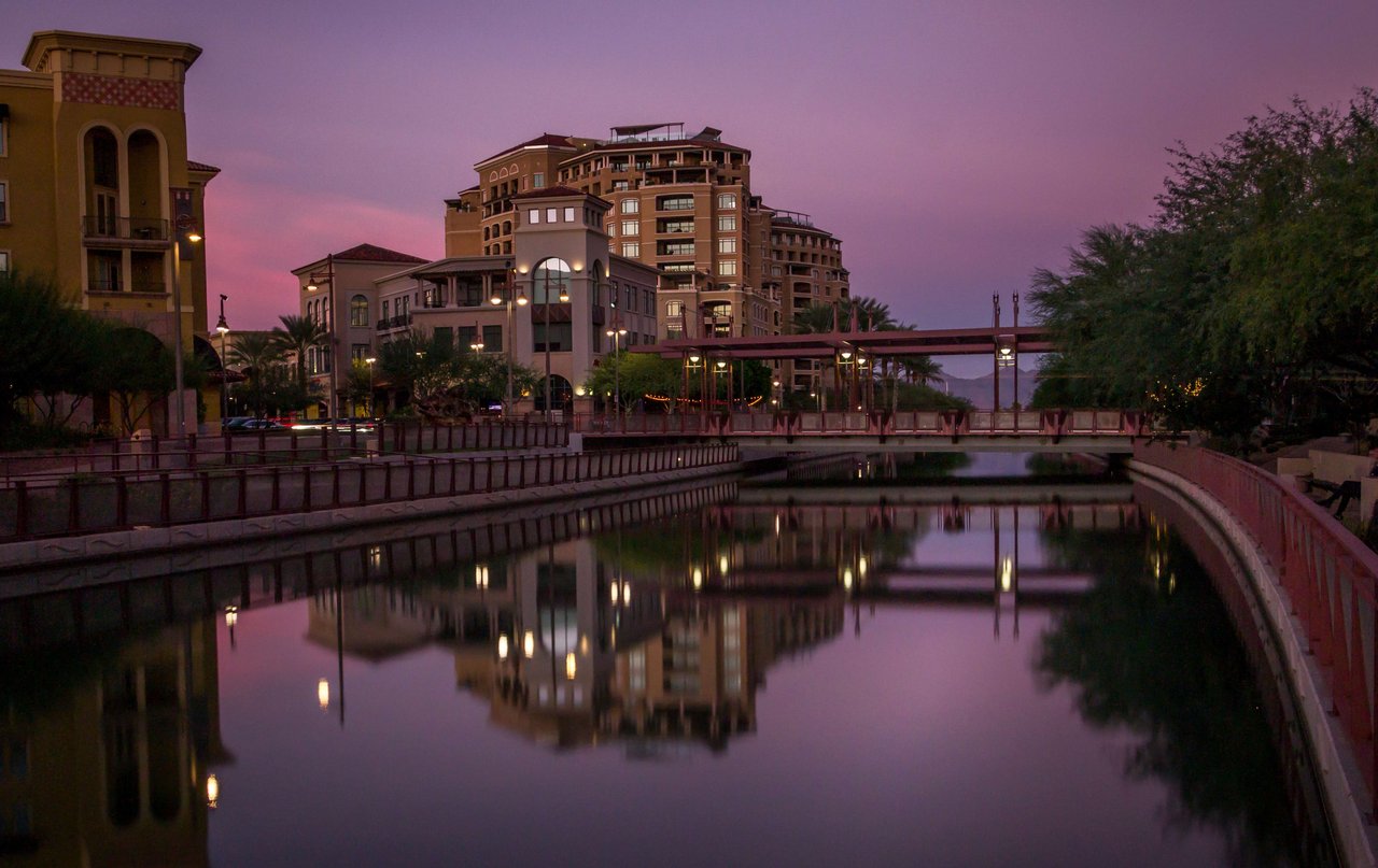 A river with a bridge and buildings under a beautiful purple sky