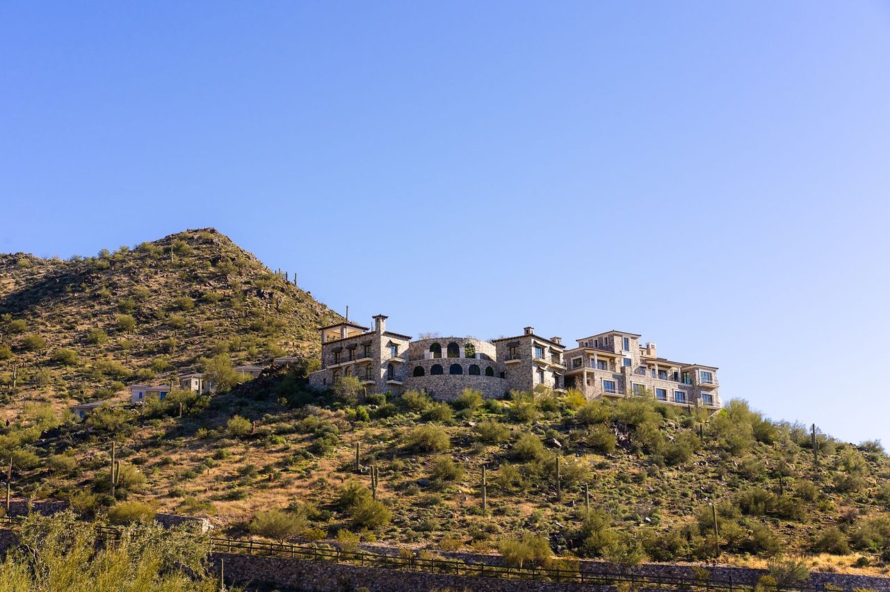 Grand estate perched on a hillside surrounded by desert landscape.