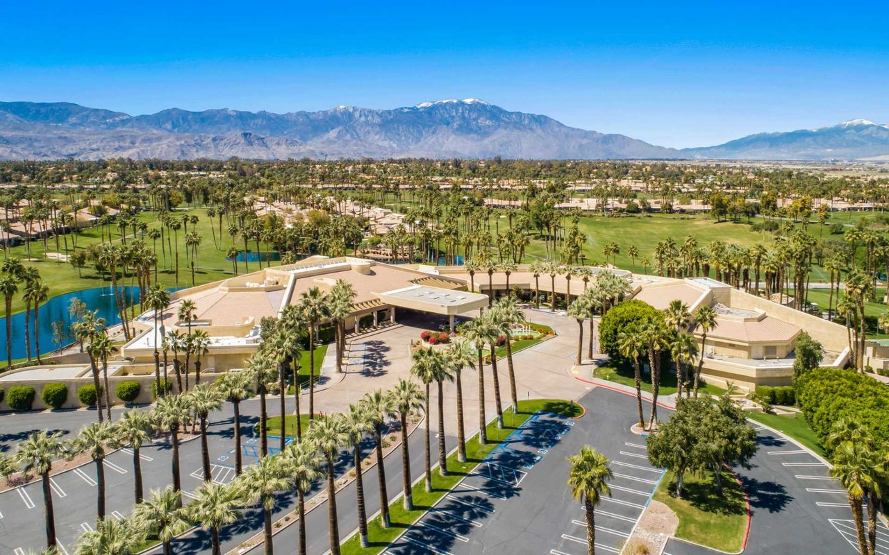 a modern clubhouse surrounded by palm trees and a golf course