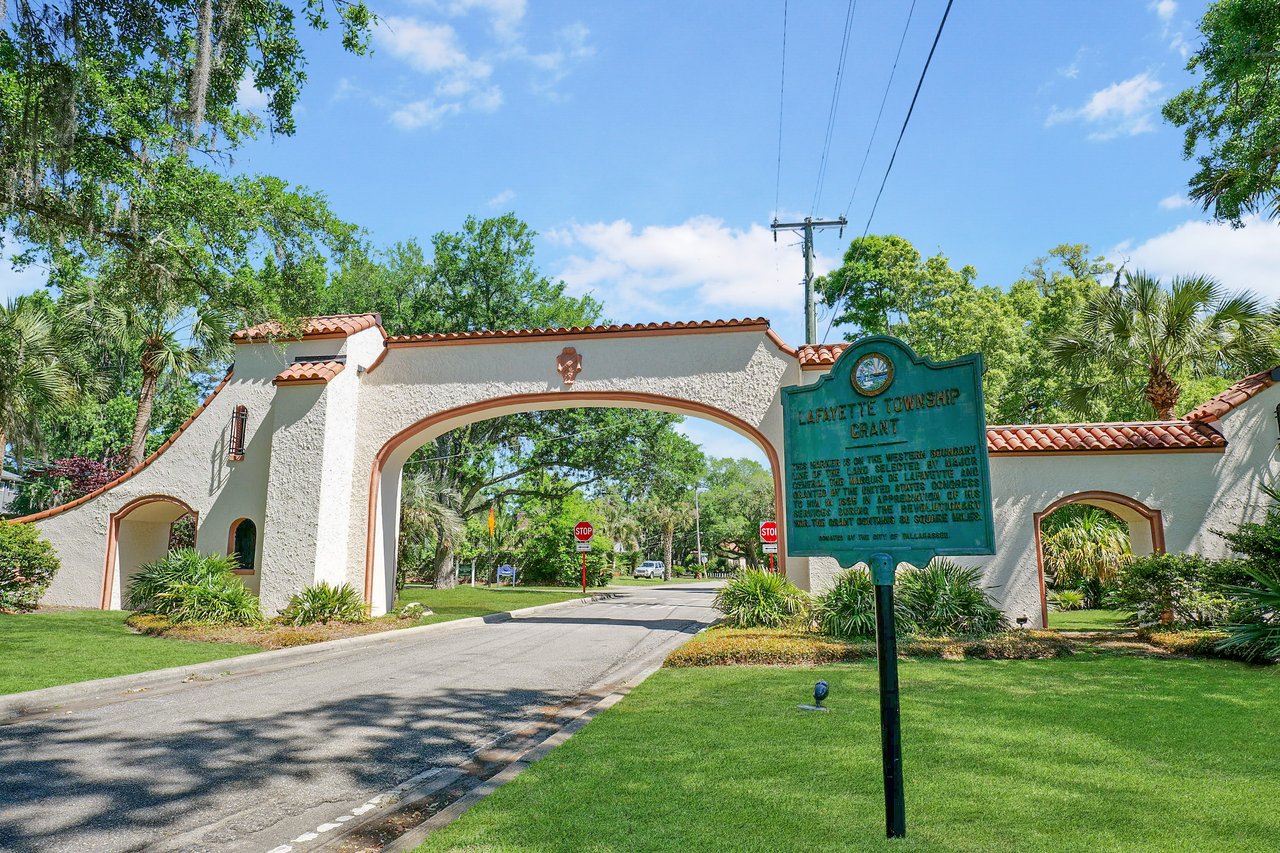 A ground-level view of an archway entrance to the Los Robles neighborhood, featuring a historic or decorative sign and lush greenery.