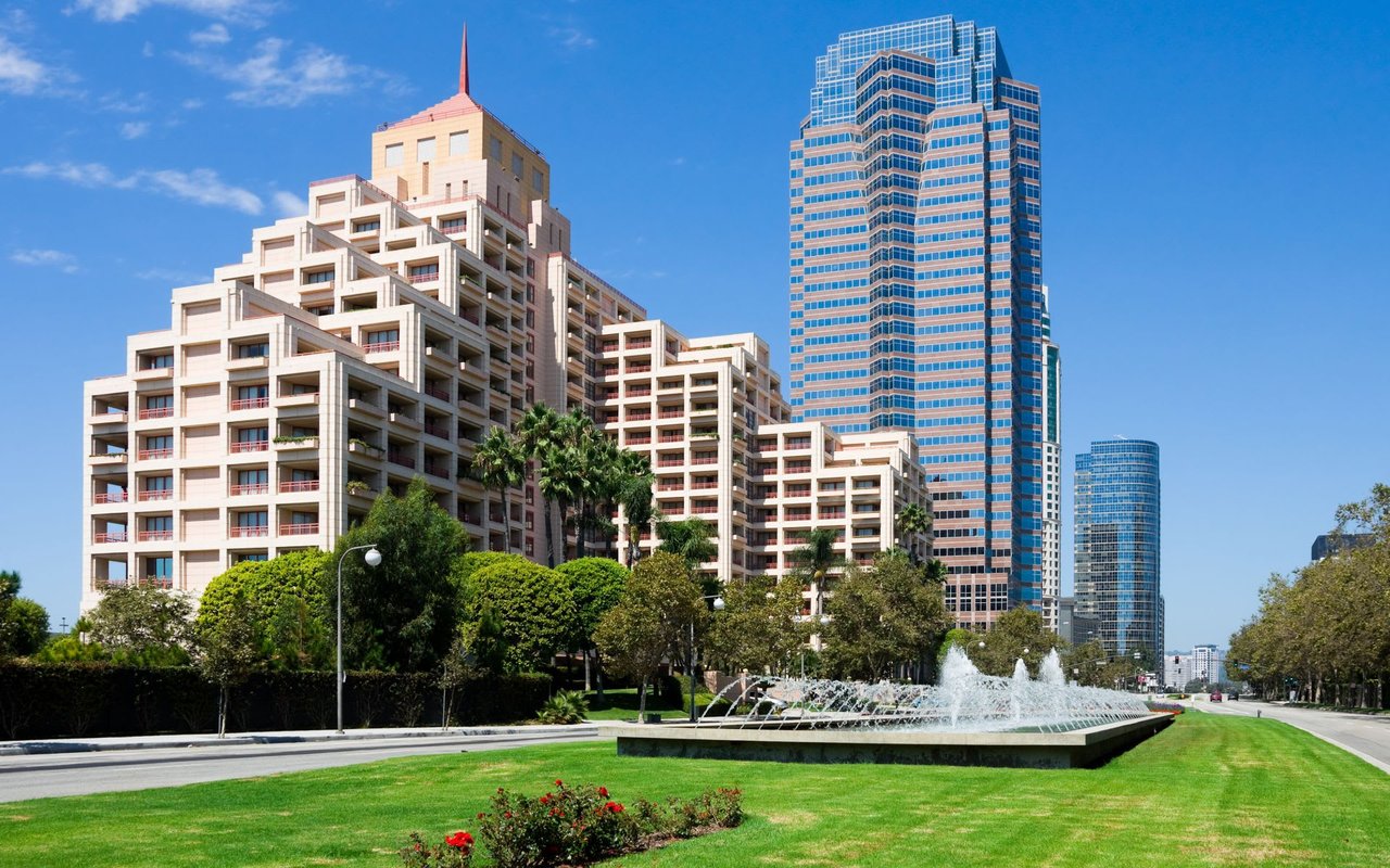 A fountain in a park with tall buildings in the background