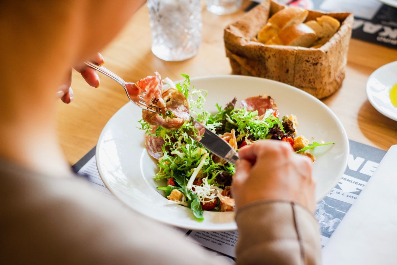 A person enjoying a salad with a fork.