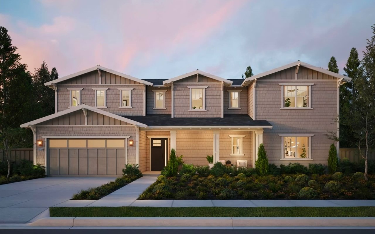 A two-story Craftsman-style house with a front porch, a two-car attached garage, a concrete driveway, and a  green lawn.