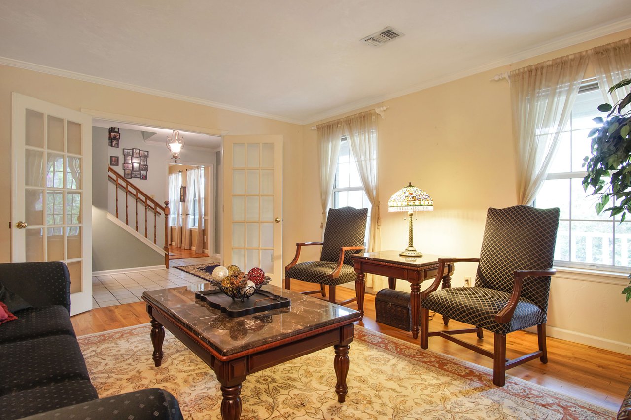 This living room features additional seating and a large coffee table, with a staircase visible in the background.