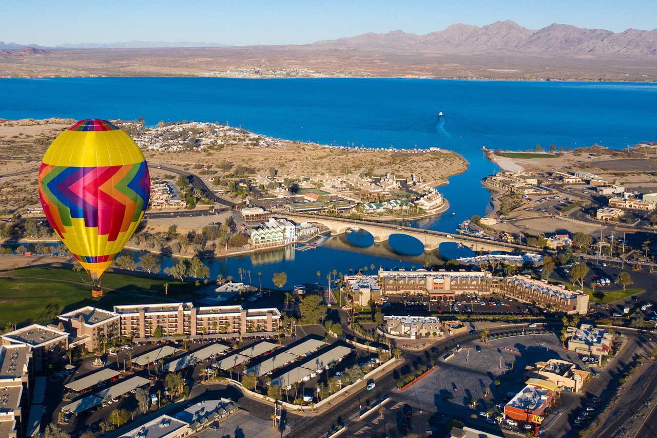 Colorful hot air balloon over a scenic lake and city, perfect for luxury homes with water views.