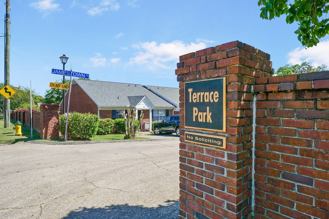  A ground-level view of a brick entrance sign for "Terrace Park," with a glimpse of the neighborhood behind it.