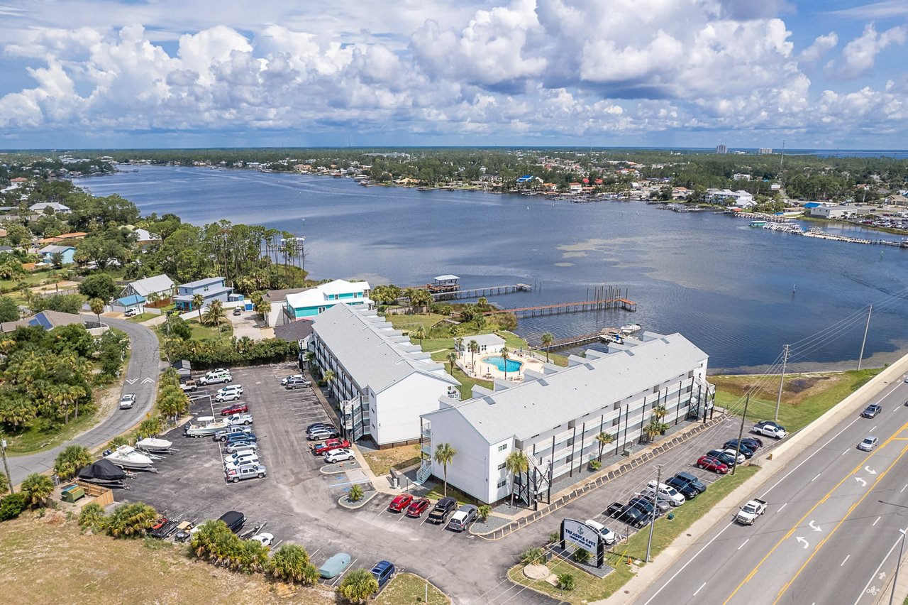 Aerial view of Treasure Cove Condos in Panama City Beach Florida with calm blue waters of the Grand Lagoon in the background.