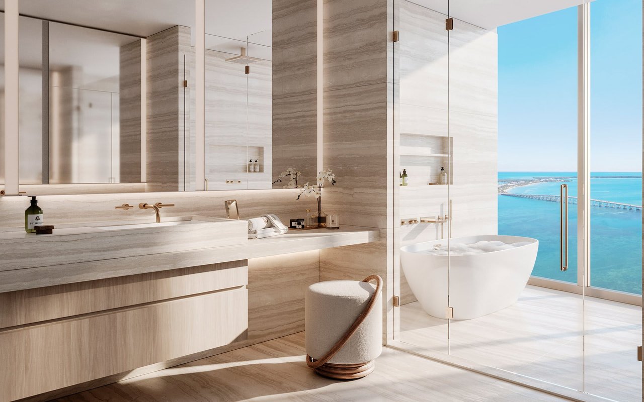 Luxury bathroom with a freestanding tub, marble finishes, and turquoise water views.