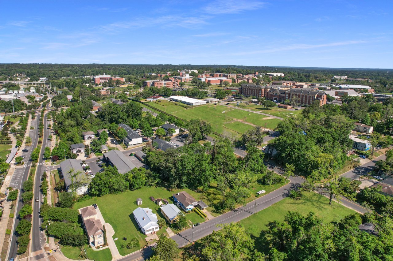  An aerial view of the Villa Mitchell community, showing houses, streets, and surrounding green spaces. The area appears well-planned with a mix of residential buildings and open areas.