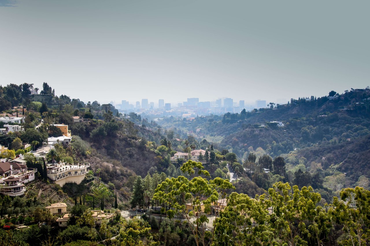 A panoramic view of rolling hills covered in lush vegetation and dotted with luxurious homes.