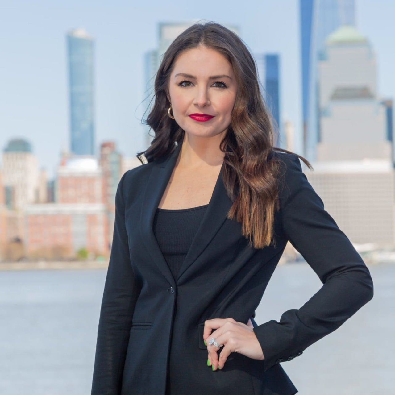 Holly Kranz, a real estate professional in a black suit, standing against the city backdrop.