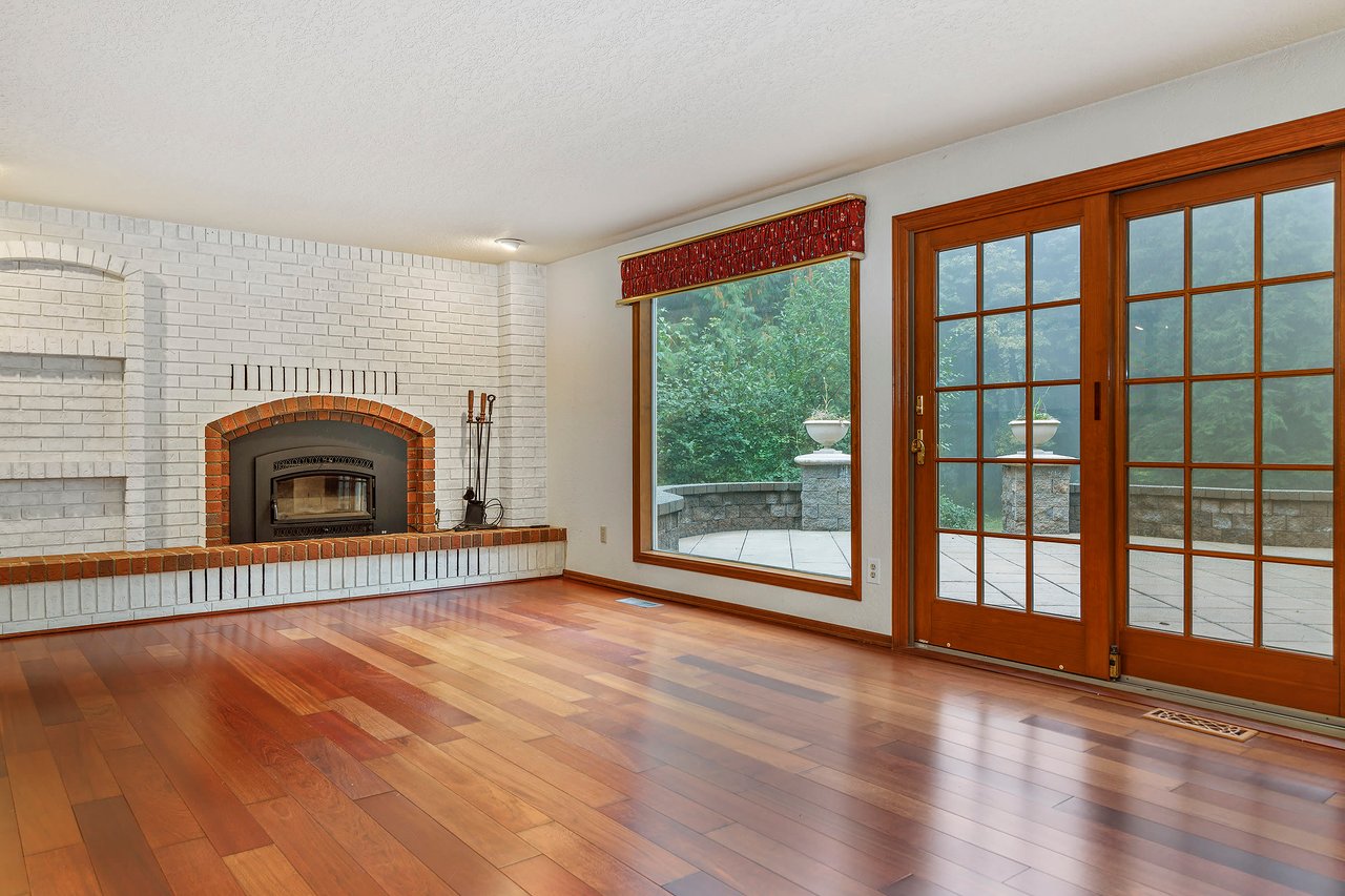 Relax in the family room, where a picture window bathes the space in natural light, and a full brick wall fireplace adds warmth and character, creating the perfect setting for cozy gatherings and relaxation.