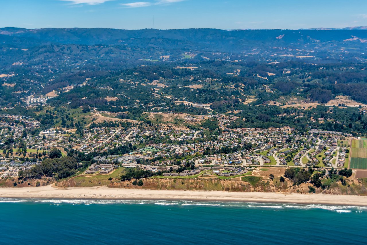 Aerial view of a coastal neighborhood with houses and a beach near the ocean.