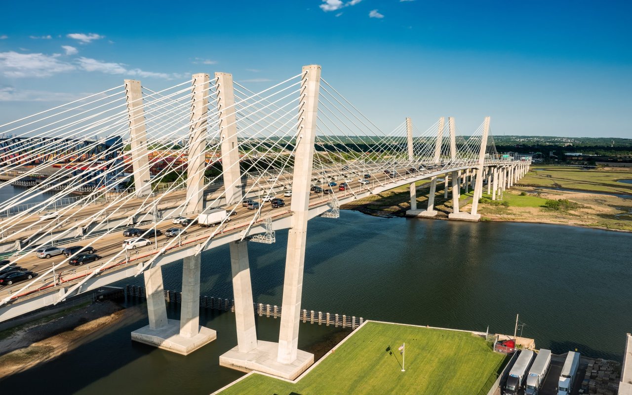 An aerial view of Goethals Bridge near Newark, New Jersey, with cars driving and a river below it.