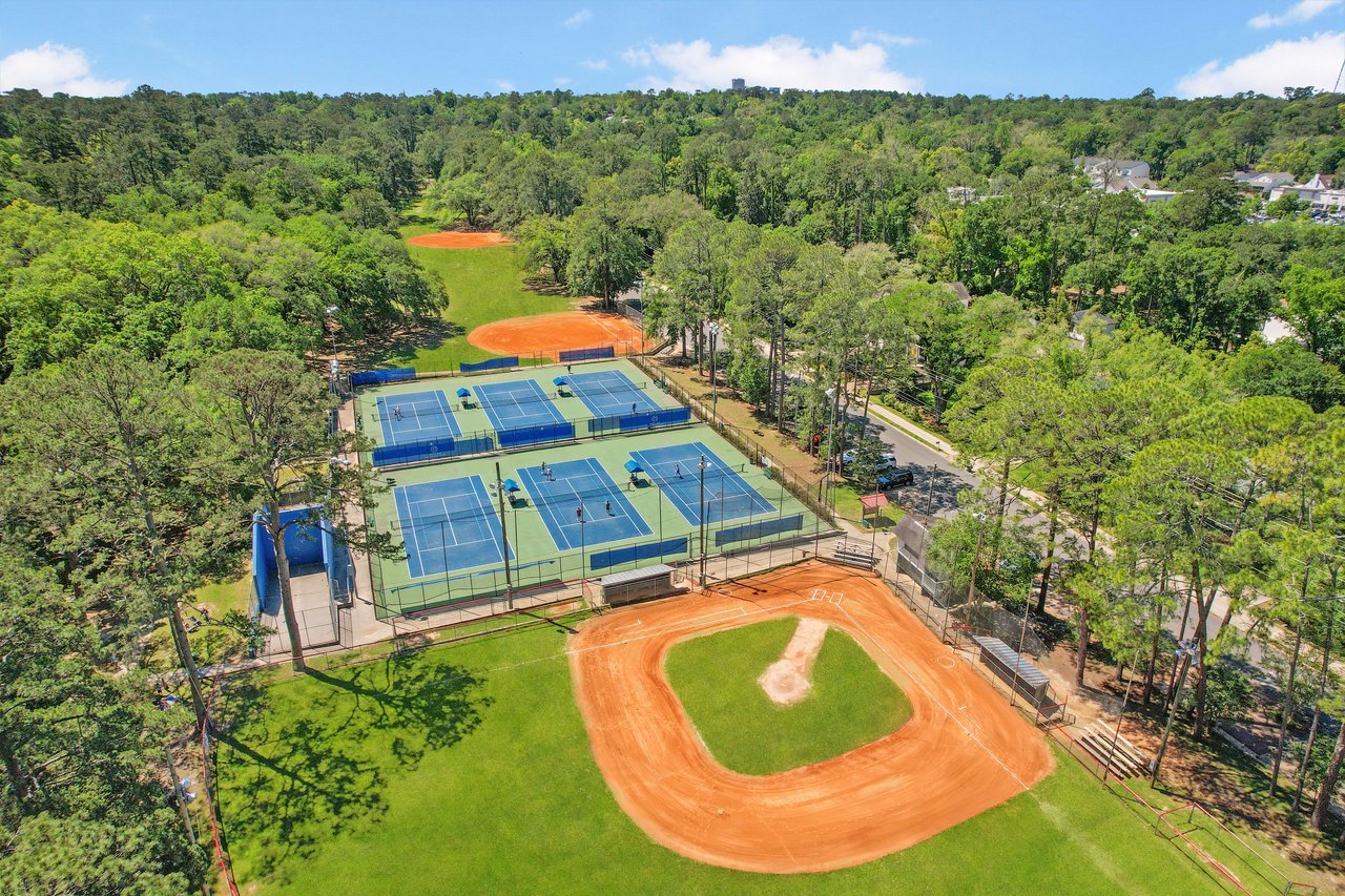 An aerial view of a recreational area in the Betton Hills neighborhood, featuring tennis courts, a baseball field, and surrounding trees.