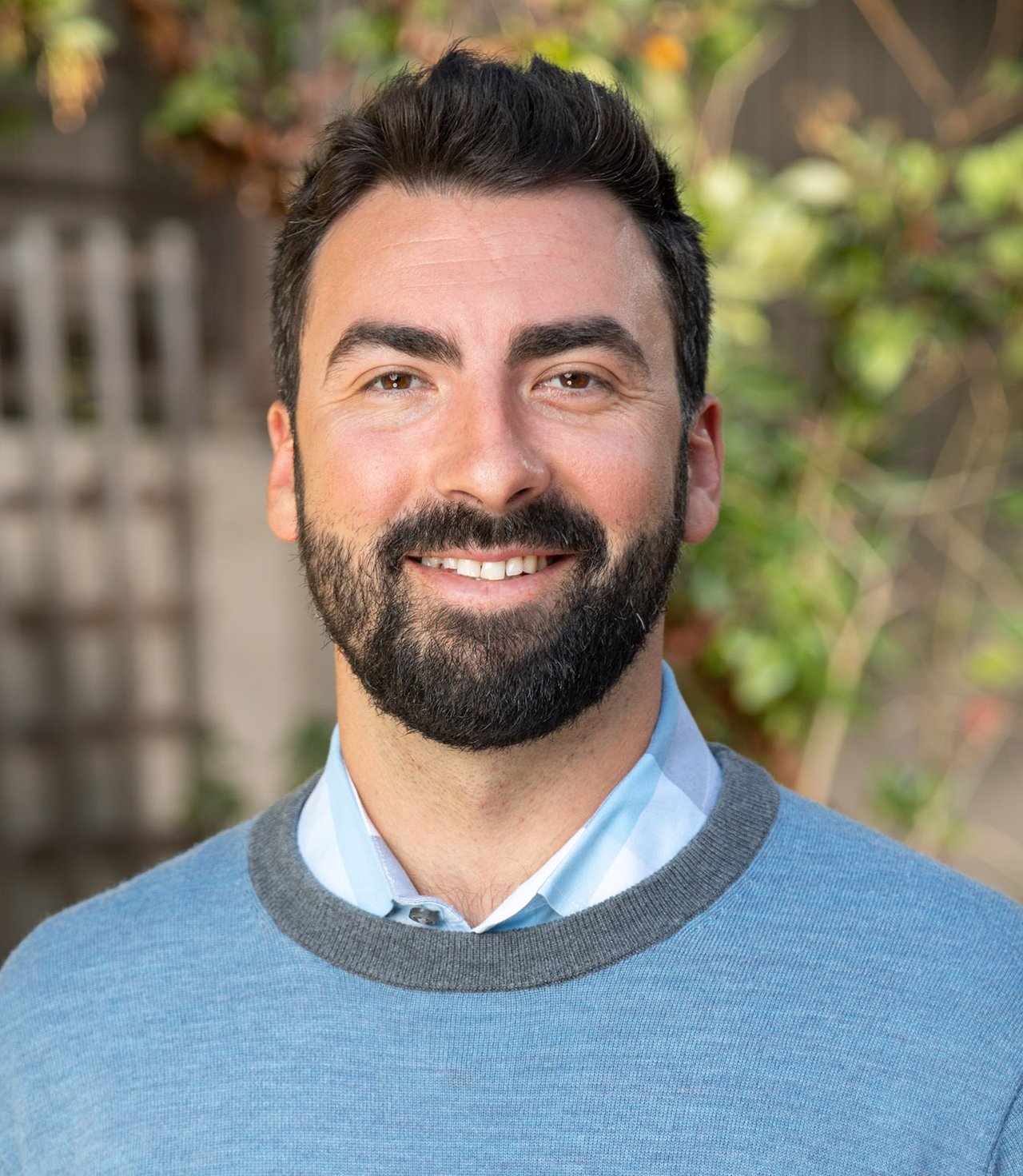 Forest DeSante smiling in a blue sweater over a light blue collared shirt.