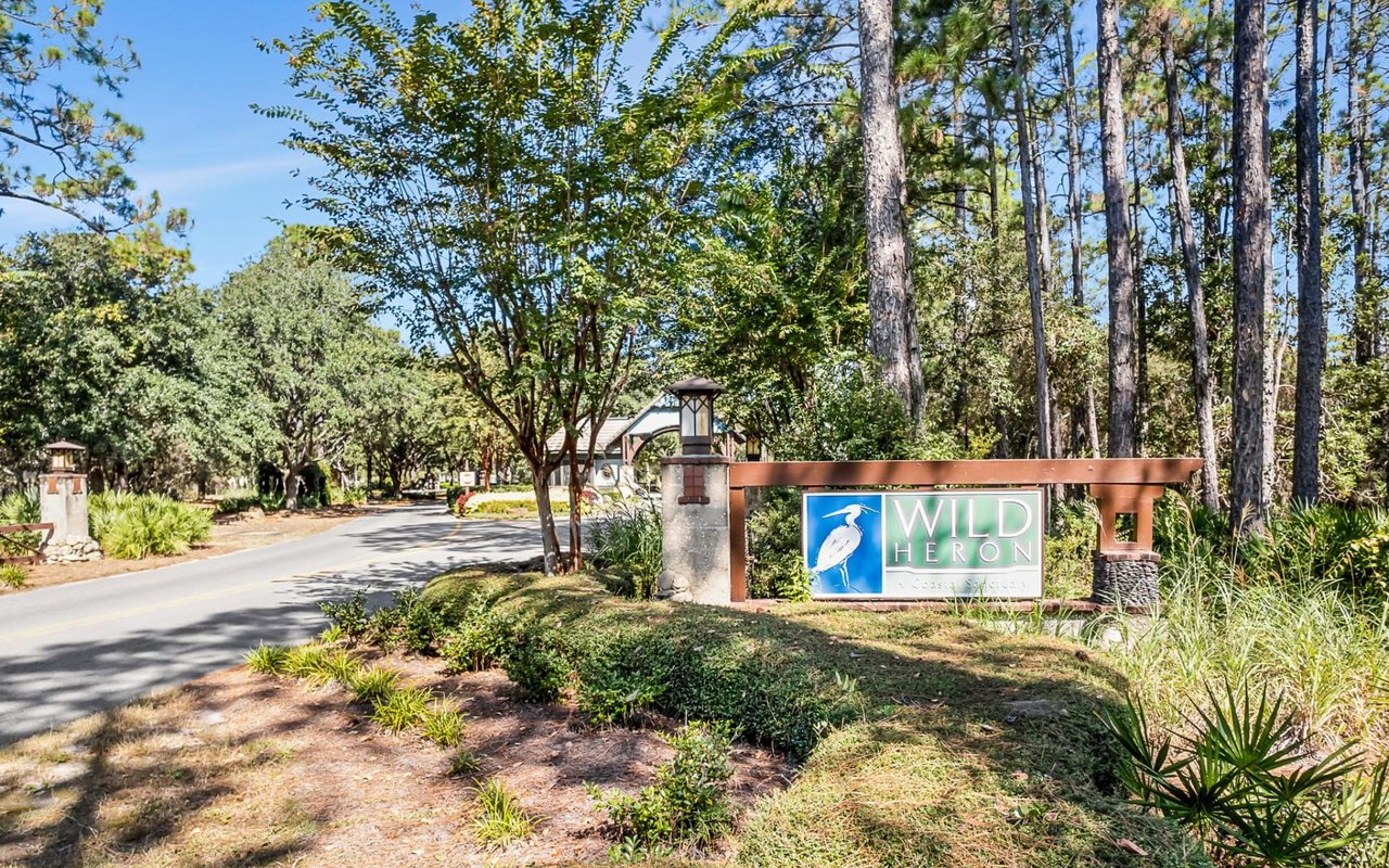 A sign that reads "Wild Heron" welcomes visitors to a gated community.