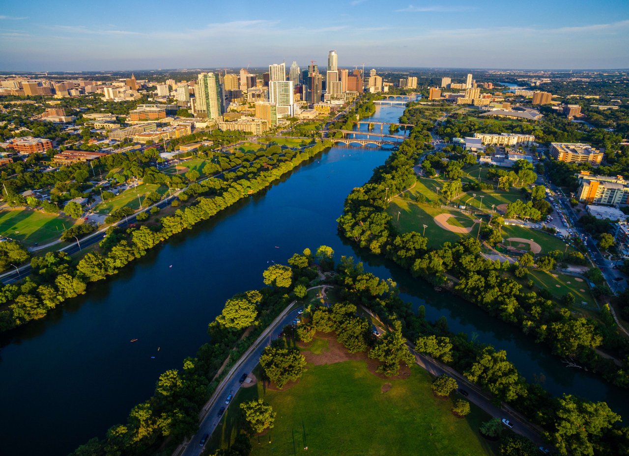 Aerial view of a vibrant city skyline with a winding river surrounded by lush greenery.