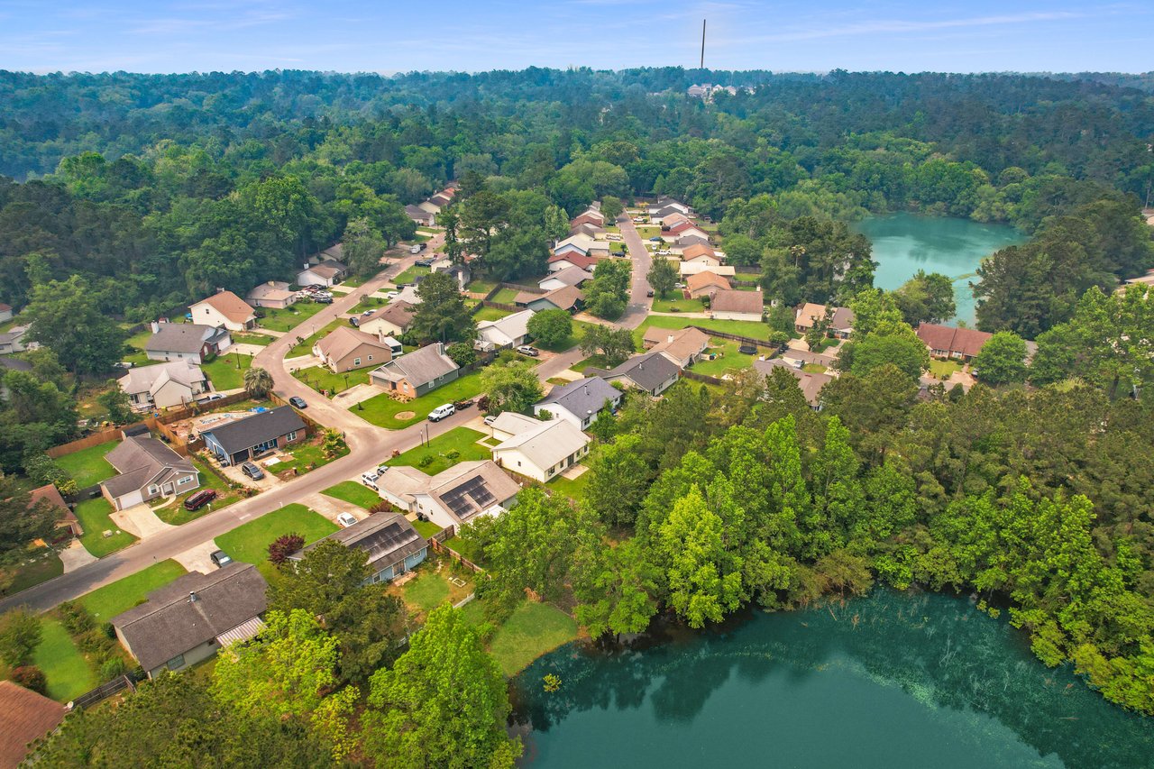 Another aerial view of Hartsfield Village, showcasing houses and streets, with a focus on the community's layout and natural surroundings.