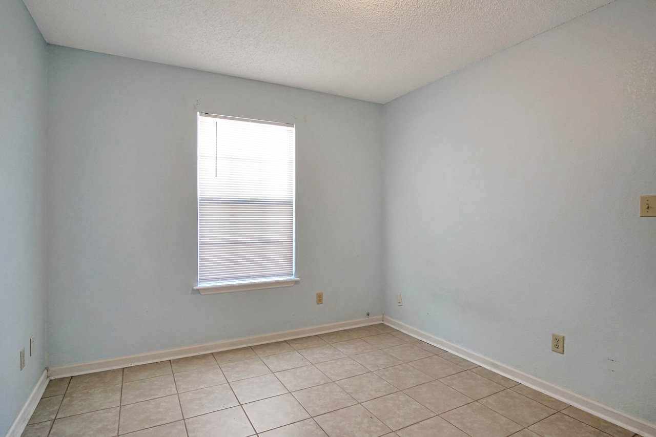 Photo of the second bedroom Featuring light blue walls, a window with blinds, a white ceiling, and lightly colored tiled flooring  at 2709 Oak Park Court, Tallahassee, Florida 32308