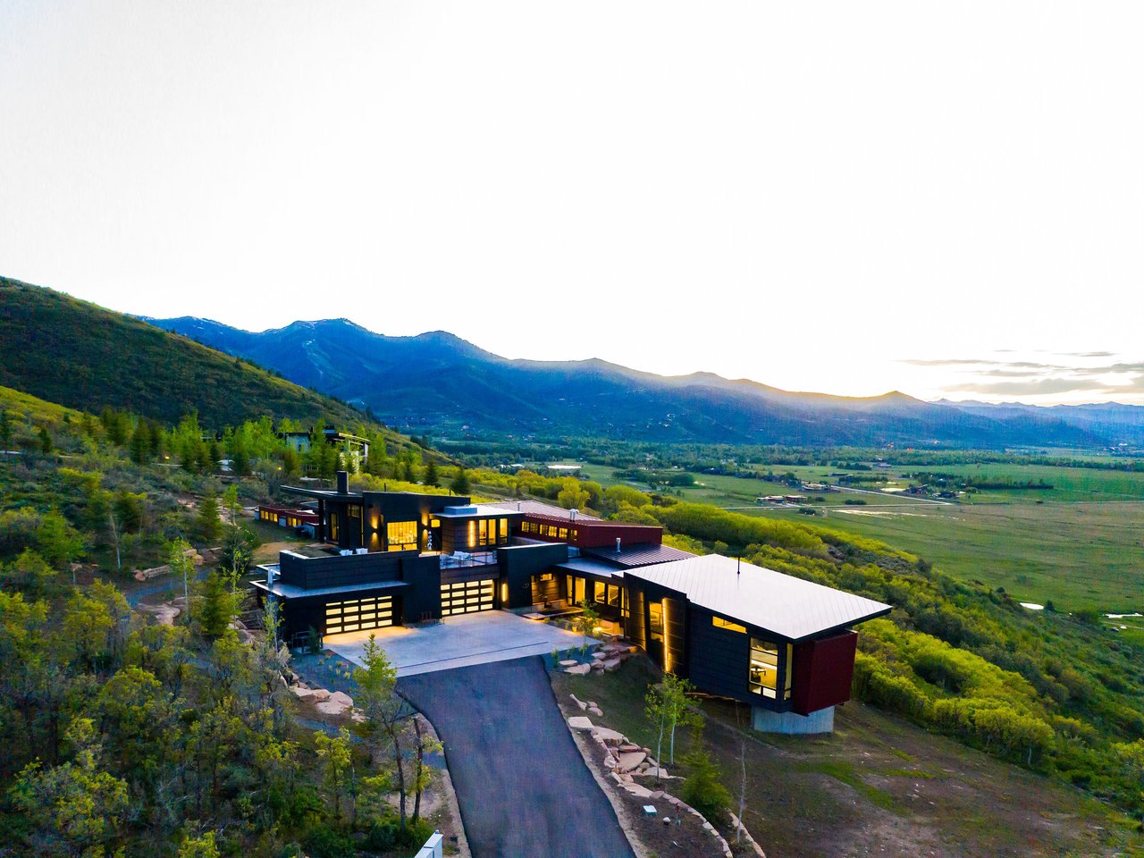 A contemporary house on a hillside overlooking a valley and mountains