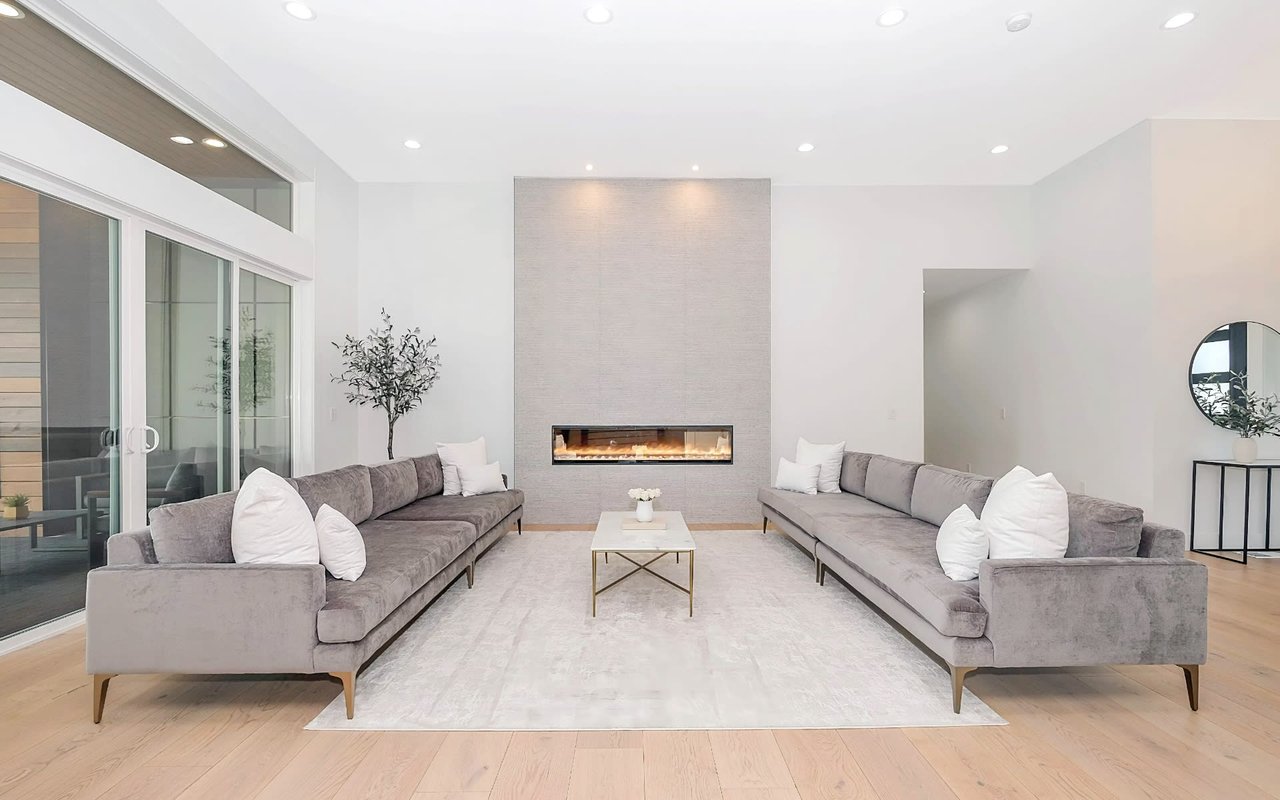 Gray sofas, white walls, sleek fireplace, bright, airy space with natural light, and calm, serene atmosphere.