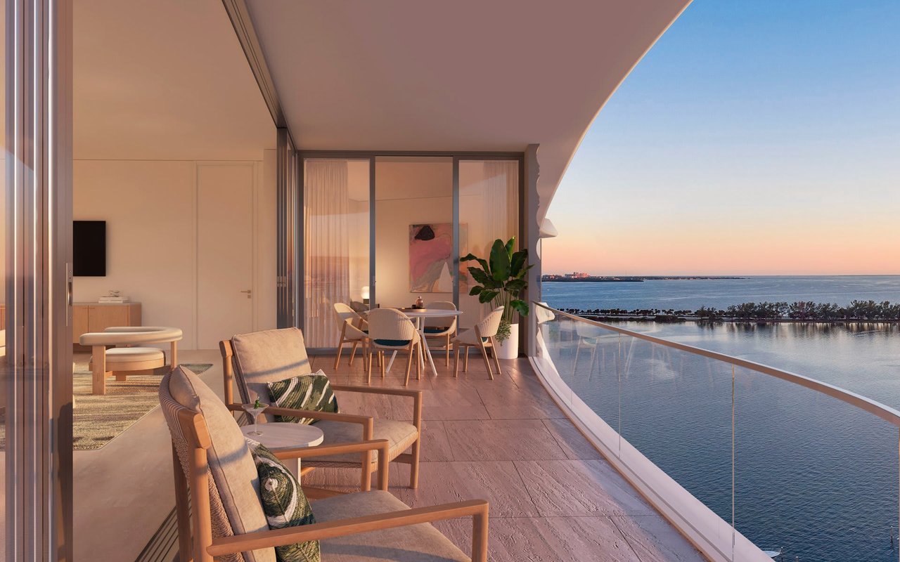 Furnished curved balcony overlooking the bay at sunset.