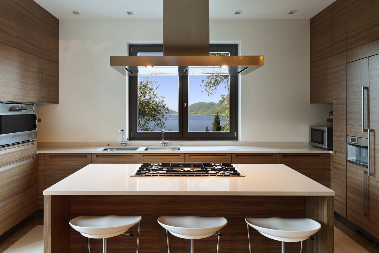  A modern kitchen featuring warm-toned wooden cabinetry and light-colored countertops