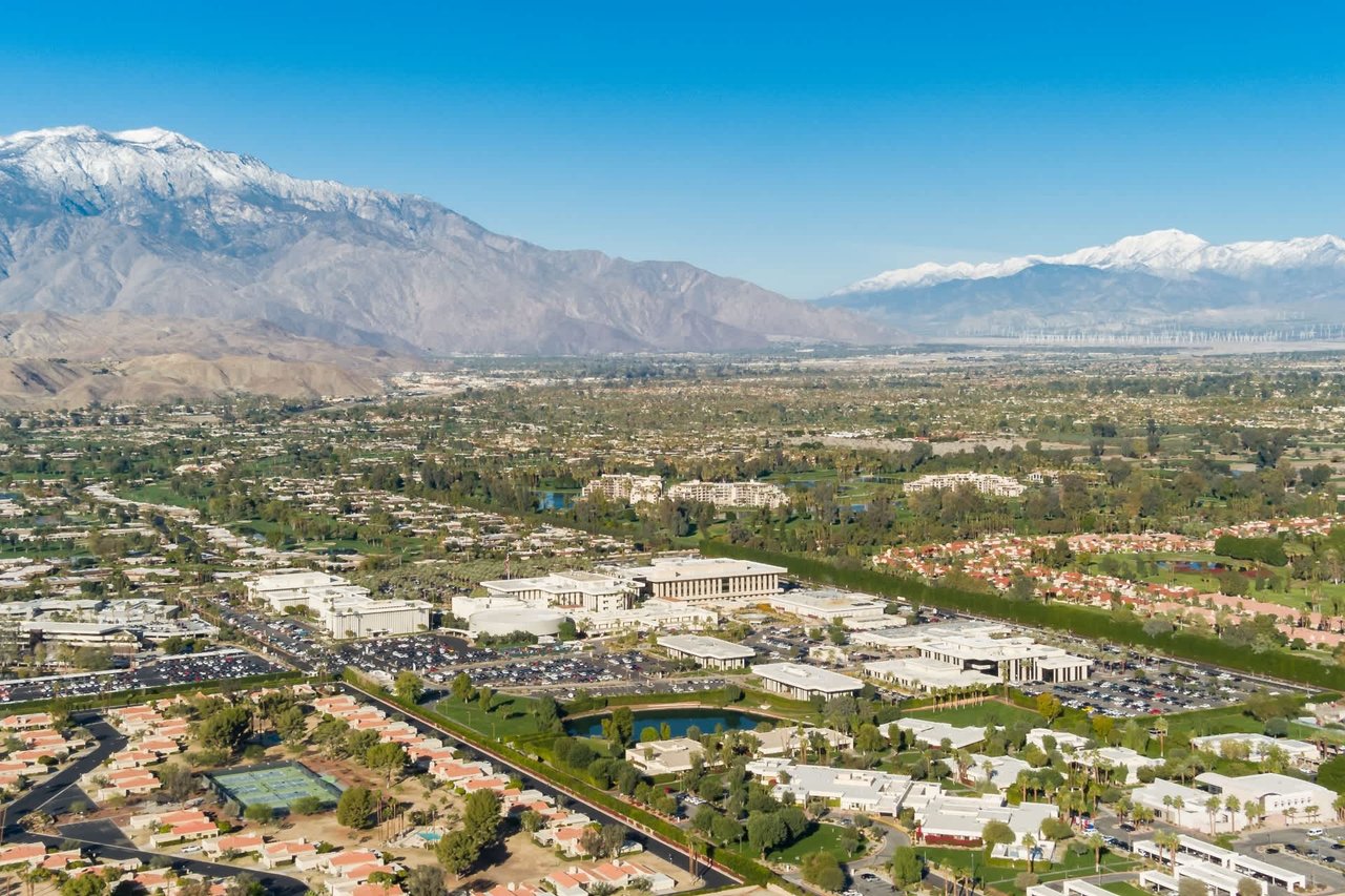 Aerial panorama of a developed valley beneath snow-dusted mountains.