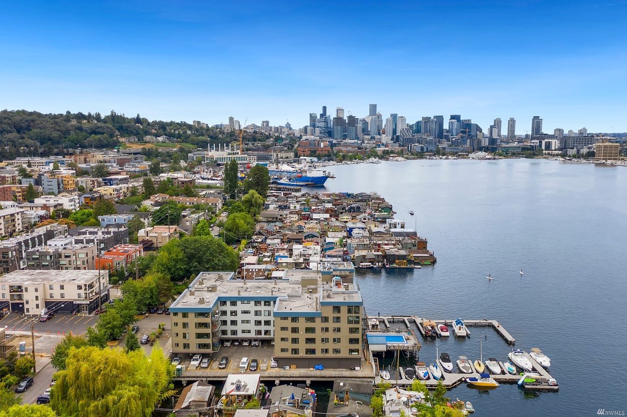 Urban waterfront condos overlooking a marina, with a bustling cityscape in the distance, exuding upscale living.