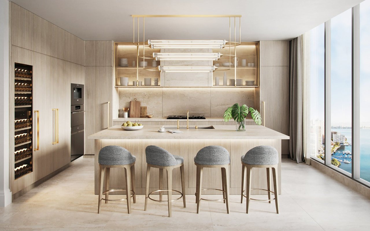 Luxury kitchen with pale wood cabinetry, a large island, and windows overlooking the water.