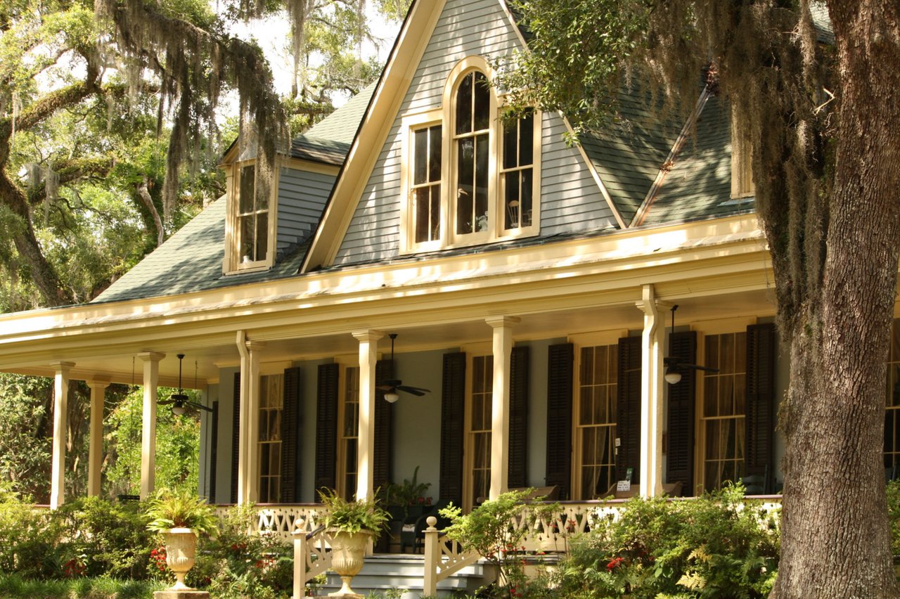 A house with a large veranda, surrounded by trees.