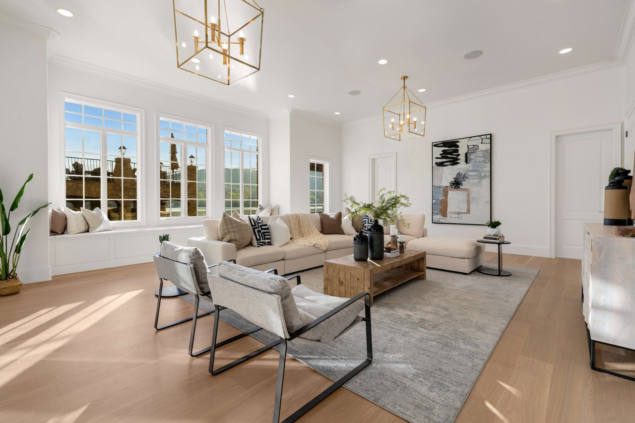 A beautifully decorated living room with a cozy couch, coffee table, and chairs near a large window.