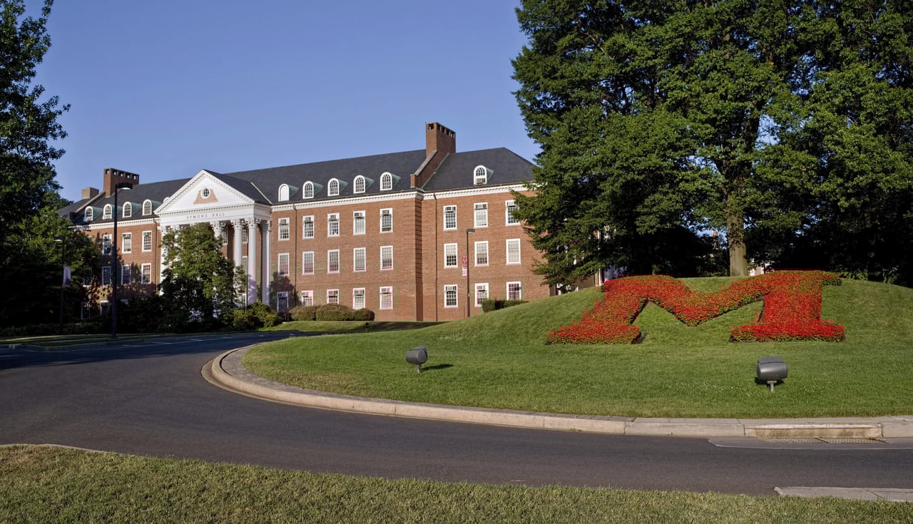  A large, stately red brick building with white columns and a black roof,