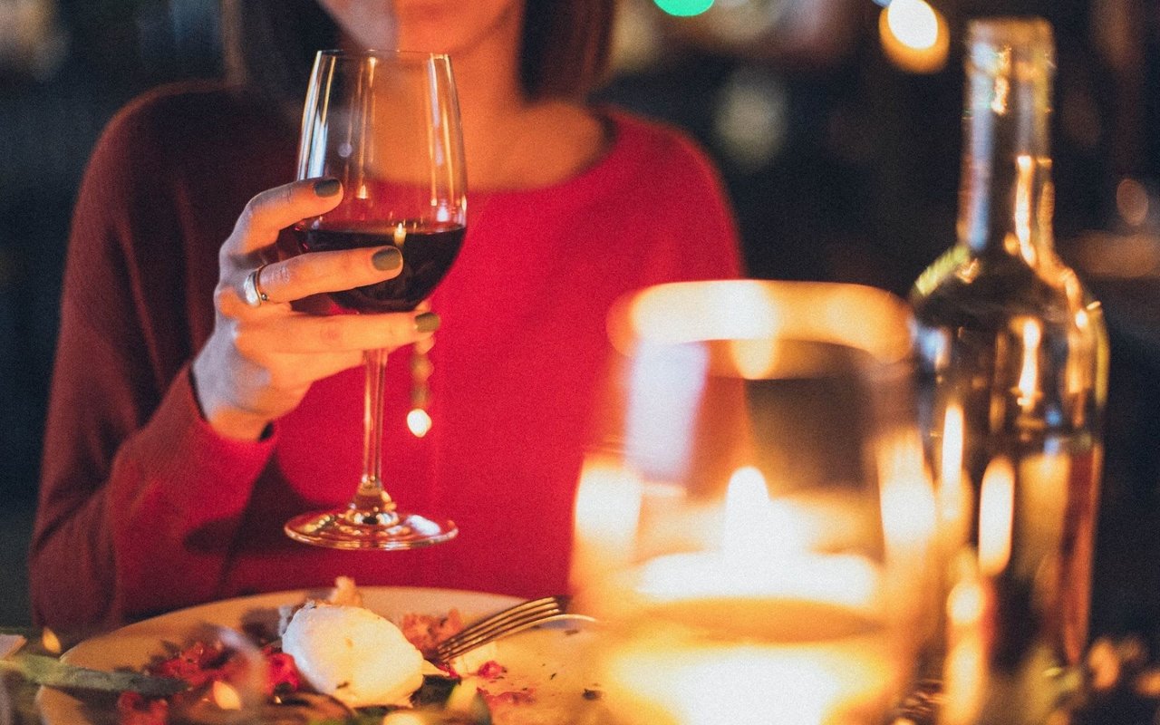 A woman gracefully holds a glass of wine, enjoying her time at a restaurant.