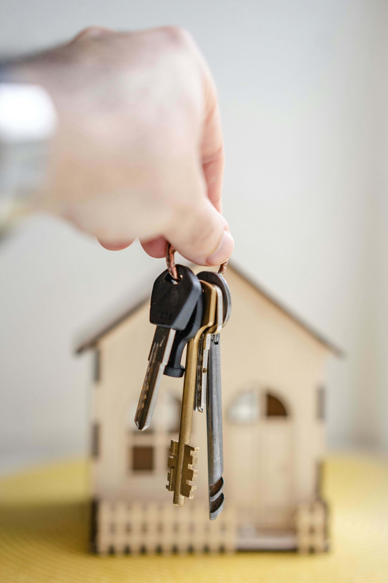 Hand holding keys in front of house