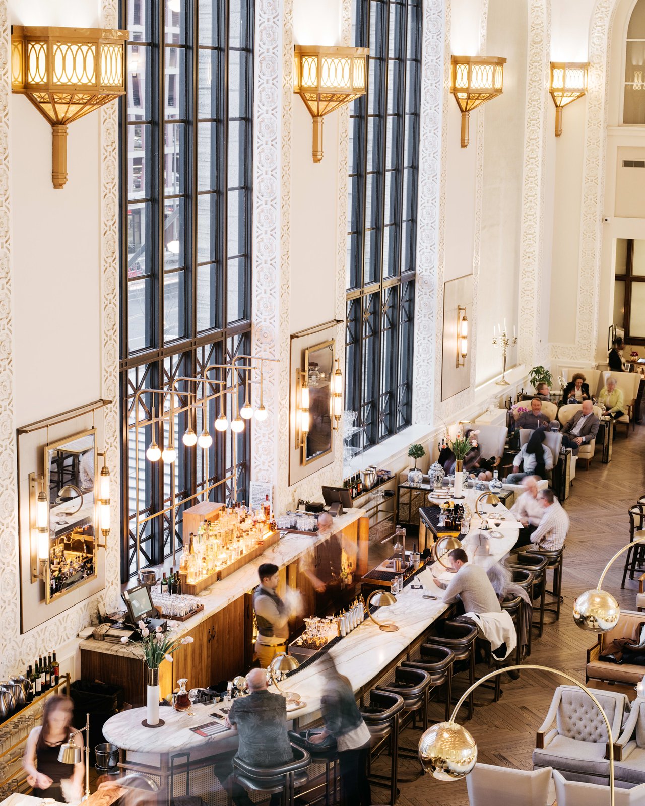 A high-end restaurant with busy food attendants and people sitting at their tables eating.