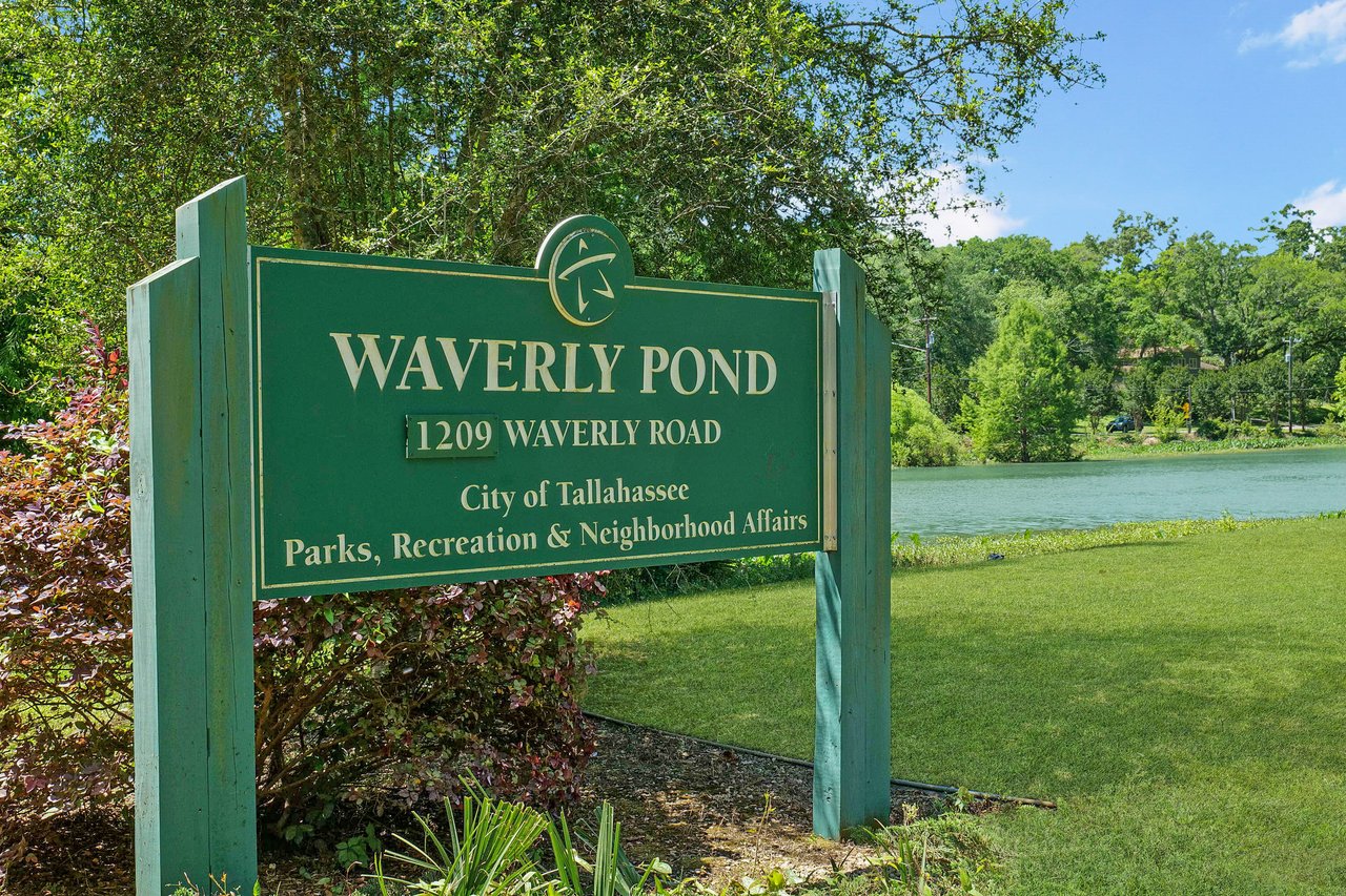  An image of a green sign for "Waverly Pond" which likely is a park or neighborhood area, with trees and a pond in the background.