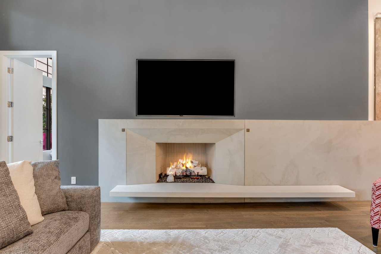 Captivating view from plush couch in living room showcasing a sleek TV and stunning modern stone fireplace for cozy ambiance.