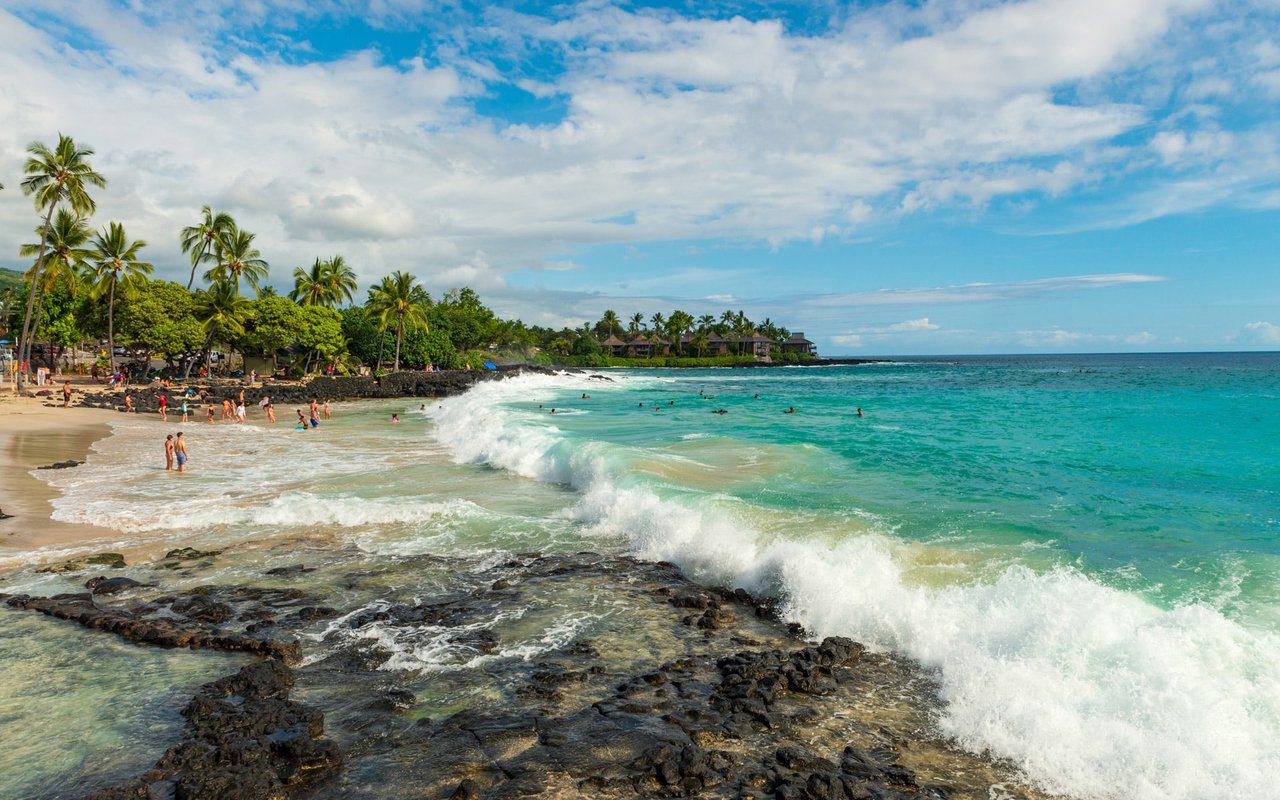 A small waves crashing in a beautiful beach shore in Ali’i Heights with bunch of people swimming