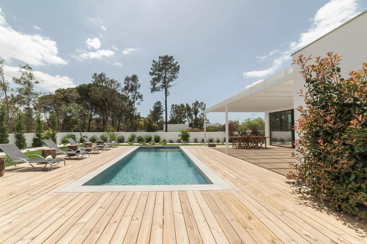 A large swimming pool with a wooden deck surrounding it.