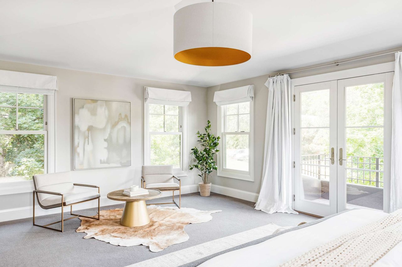 Modern seating area with gold accent table, white chairs, and French doors to balcony