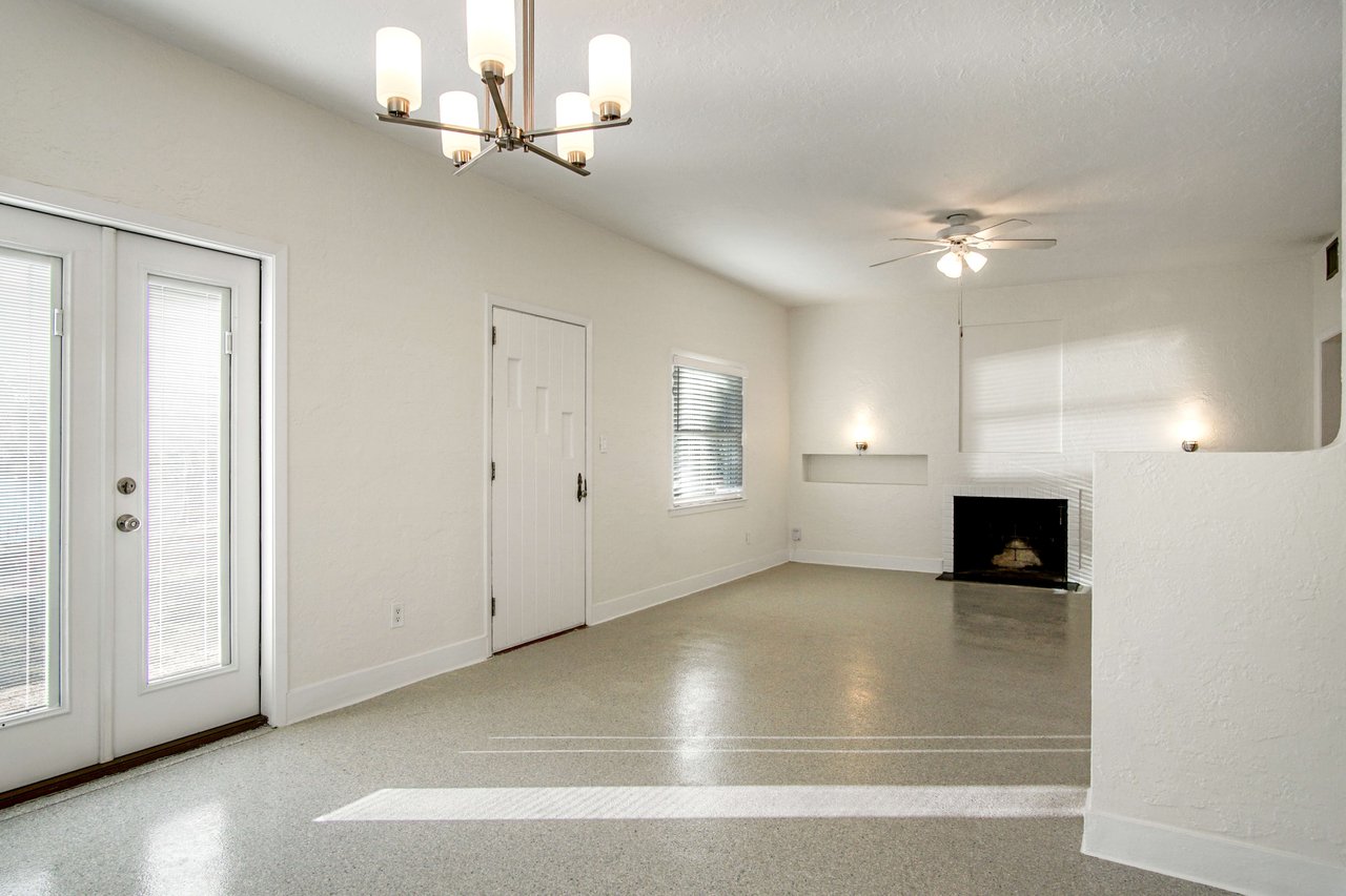 The front entrance area of the home, showing a door leading outside and a spacious interior with tiled flooring and light fixtures.
