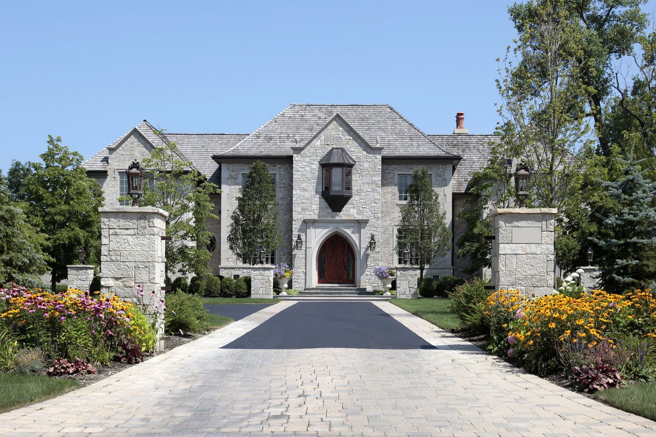 A close-up of a large stone house with a gray roof.